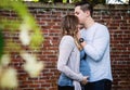 Pregnant couple kissing in front of brick wall Royalty Free Stock Photo