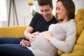 Pregnant Couple Sitting On Sofa With Man Touching Womans Stomach Royalty Free Stock Photo