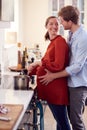 Pregnant Couple With Woman With Prosthetic Arm Preparing Meal In Kitchen Together Royalty Free Stock Photo