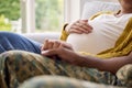 Pregnant Couple With Woman Sitting Next To Army Husband In Uniform Holding Hands Home On Leave Royalty Free Stock Photo