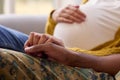 Pregnant Couple With Woman Sitting Next To Army Husband In Uniform Holding Hands Home On Leave Royalty Free Stock Photo