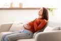 Pregnant european lady rests peacefully on living room couch indoor