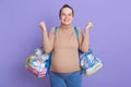 Pregnant European woman with hair bun leaving for maternity hospital, expressing joy and happiness, clenched fists, wearing beige Royalty Free Stock Photo