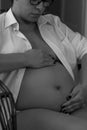 Pregnant female cuddling belly in bedroom at home black and whit Royalty Free Stock Photo