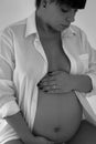 Pregnant female cuddling belly in bedroom at home black and whit Royalty Free Stock Photo