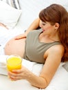 Pregnant female relaxing on sofa with juice