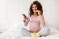 Pregnant Female Resting On Bed At Home, Watching Tv And Eating Popcorn Royalty Free Stock Photo