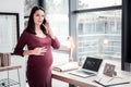 Pregnant geographer on maternity leave calling her experienced colleages Royalty Free Stock Photo