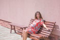 The pregnant girl basks in the sun. The concept of warm leisure - a beautiful pregnant girl with long hair, basking in a red dress Royalty Free Stock Photo