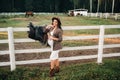 A pregnant girl with a big belly in a hat next to horses near a paddock in nature.Stylish pregnant woman in a brown dress with Royalty Free Stock Photo