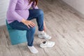 A pregnant girl with a big belly puts on sneakers on her feet. The concept of discomfort and inconvenience when bending over and