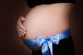 Pregnant girl with a blue ribbon at the bottom of her stomach