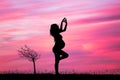 A pregnant girl doing yoga at sunset