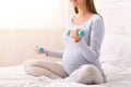 Pregnant Girl Exercising With Dumbbells Sitting At Home, Cropped