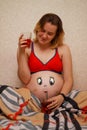 pregnant girl with a funny drawn face on her stomach.