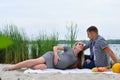 Pregnant girl and guy on a picnic by the river Royalty Free Stock Photo