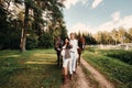 A pregnant girl in a hat and her husband in white clothes stand next to horses in the forest in nature.Stylish pregnant woman with Royalty Free Stock Photo