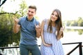 Pregnant girl and her boyfriend have fun on the pier, laugh and show gestures on their hands at sunset Royalty Free Stock Photo