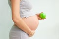 Pregnant girl holding a green apple. nutrition during pregnancy. Vitamins and pregnancy. Source of iron, pregnant anemia.