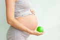 Pregnant girl holding a green apple. nutrition during pregnancy. Vitamins and pregnancy. Source of iron, pregnant anemia.