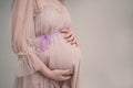 A pregnant girl is holding her belly. A young mother is expecting the birth of a child. Woman gently hugs her baby in Royalty Free Stock Photo