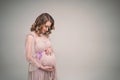 A pregnant girl is holding her belly. A young mother is expecting the birth of a child. Woman gently hugs her baby in Royalty Free Stock Photo