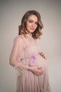 A pregnant girl is holding her belly. A young mother is expecting the birth of a child. Woman gently hugs her baby in Royalty Free Stock Photo