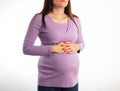 Pregnant girl holding her stomach during pregnancy on a white background. The concept of discomfort and pain in the Royalty Free Stock Photo