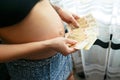 Pregnant girl holding money. Ukrainian bills, hryvnia. Social problems are paid medicine