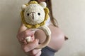 A pregnant girl holds out a knitted rattle in the form of a lion to the camera.