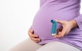 Pregnant girl with an inhaler in her hand on the background of her stomach. The concept of exacerbation of asthma in Royalty Free Stock Photo