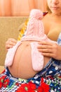 Pregnant girl keeps baby knitted things on her stomach