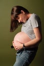 Pregnant girl leaned over and hugs her belly