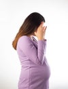 A pregnant girl in a purple blouse on a white background holds her head. Dizziness in pregnancy and vegetative dystonia. Tension Royalty Free Stock Photo