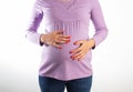 A pregnant girl with a purple sweater holds her swollen belly. Concept of digestive problems in pregnant women Royalty Free Stock Photo
