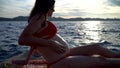 Pregnant girl putting suncreen on her belly at sea