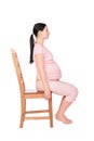 Pregnant girl sits on chair sideview