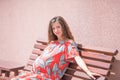 A pregnant girl is sitting on a bench. place for the inscription. Beautiful pregnant girl in dress