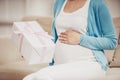 Pregnant Girl Sitting on Couch with Gift in Hand.