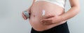 Pregnant woman applying cream on her belly for healing and skin elasticity