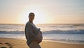 Pregnant girl standing sunset holding tummy close up. Future mother posing beach Royalty Free Stock Photo