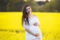 Pregnant girl on a yellow background. looks at his stomach, imagines his unborn child. Maternity concept Royalty Free Stock Photo