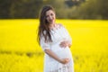 Pregnant girl on a yellow background. looks at his stomach, imagines his unborn child. Maternity concept Royalty Free Stock Photo