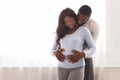 Pregnant smiling black woman and her husband cuddling at home Royalty Free Stock Photo