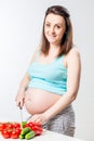 Pregnant happy woman cuts fresh vegetables