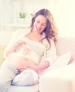 Pregnant happy woman holding baby shoes