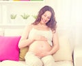 Pregnant happy woman sitting on a sofa Royalty Free Stock Photo