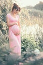 Pregnant happy Woman touching her belly. Full length Pregnant beauty young mother outdoor portrait, caressing her belly
