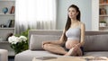 Pregnant lady doing yoga breathing exercises, relaxing at home, health care