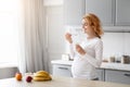 Pregnant lady eating yogurt in the kitchen Royalty Free Stock Photo